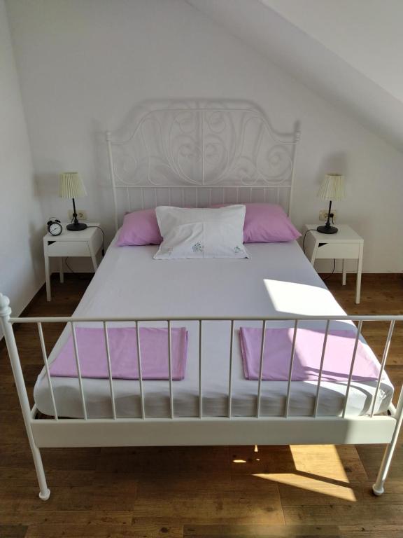 un letto bianco con cuscini viola in una camera da letto di Apartman Luka a Viganj