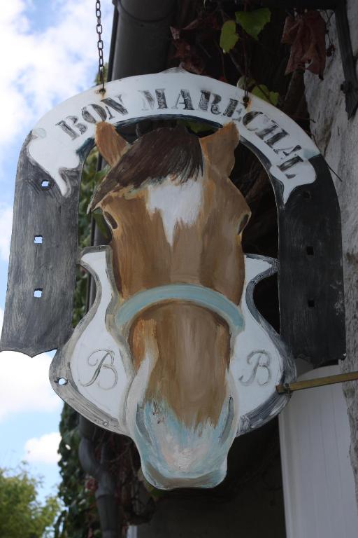 un panneau avec un cheval sur le côté d'un bâtiment dans l'établissement Au bon maréchal, à Giverny