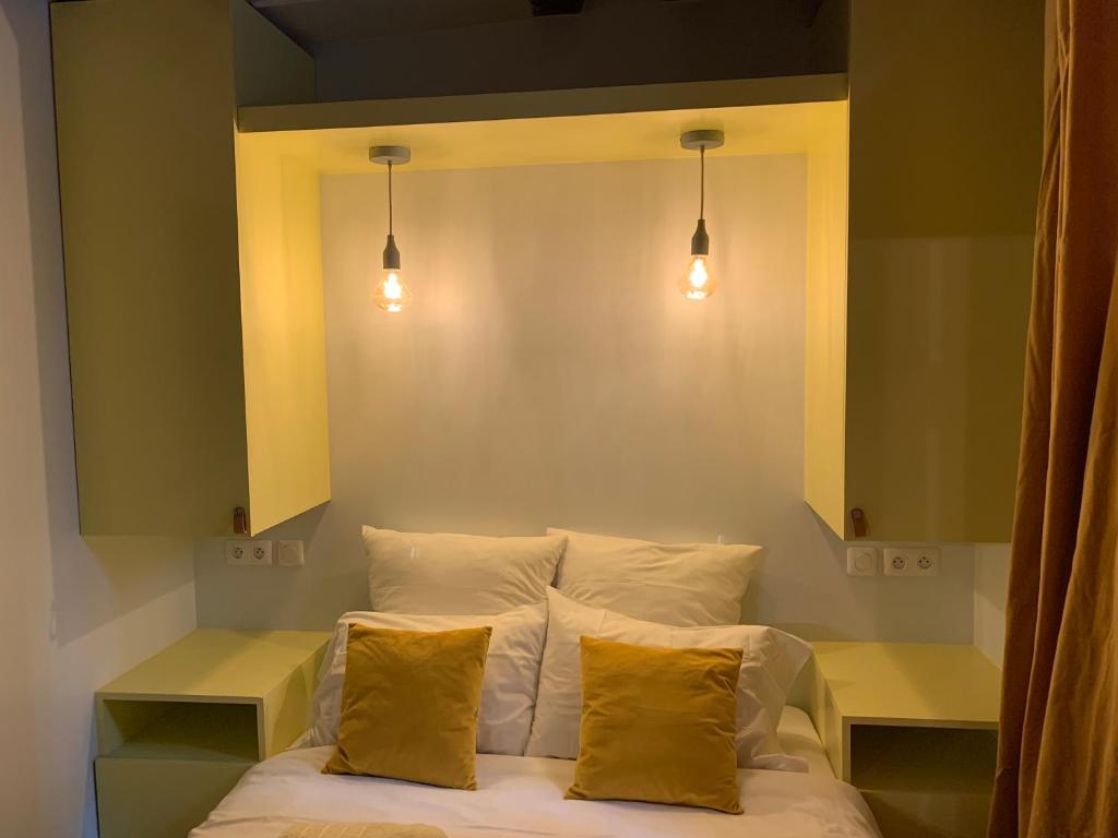 - un lit avec 2 oreillers et 2 lumières au-dessus dans l'établissement Paris 6 SAINT GERMAIN SEINE, à Paris