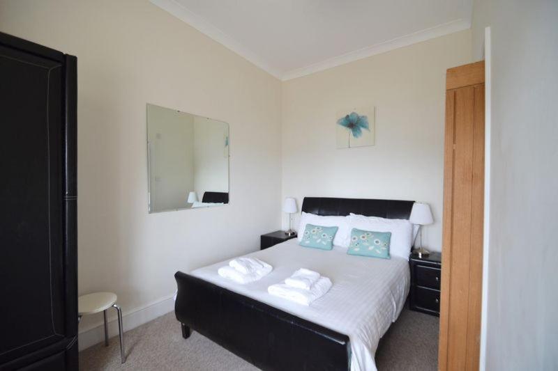 a bedroom with a bed and a dresser at Rosemorran Holiday Apartments in St Ives