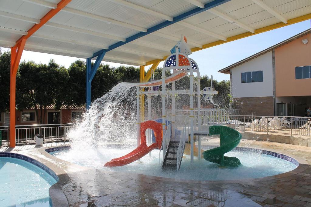 un tobogán de agua en una piscina con una fuente en diRoma Fiori com Roupa de Cama Parque Aquatico Academia e Garagem, en Caldas Novas