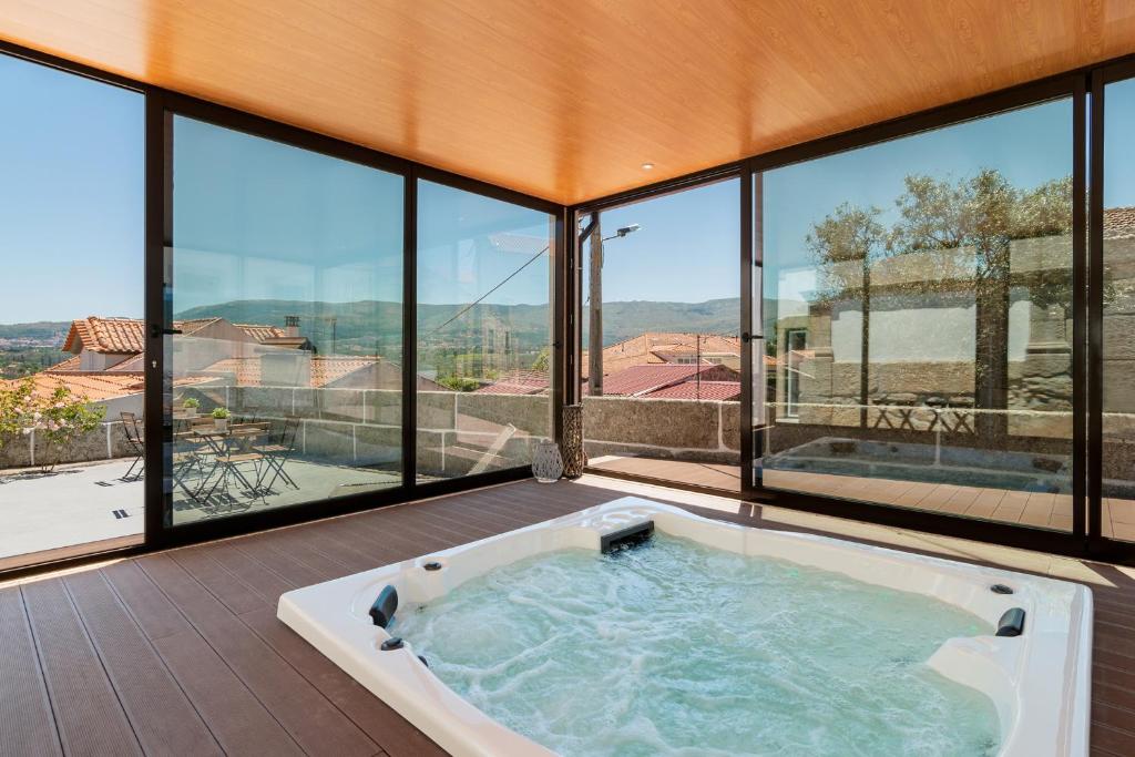 uma banheira de hidromassagem num quarto com janelas grandes em Casa de Lagarinhos JACUZZI SPA JOGOS GYM - SERRA DA ESTRELA - SEIA - GOUVEIA em Gouveia