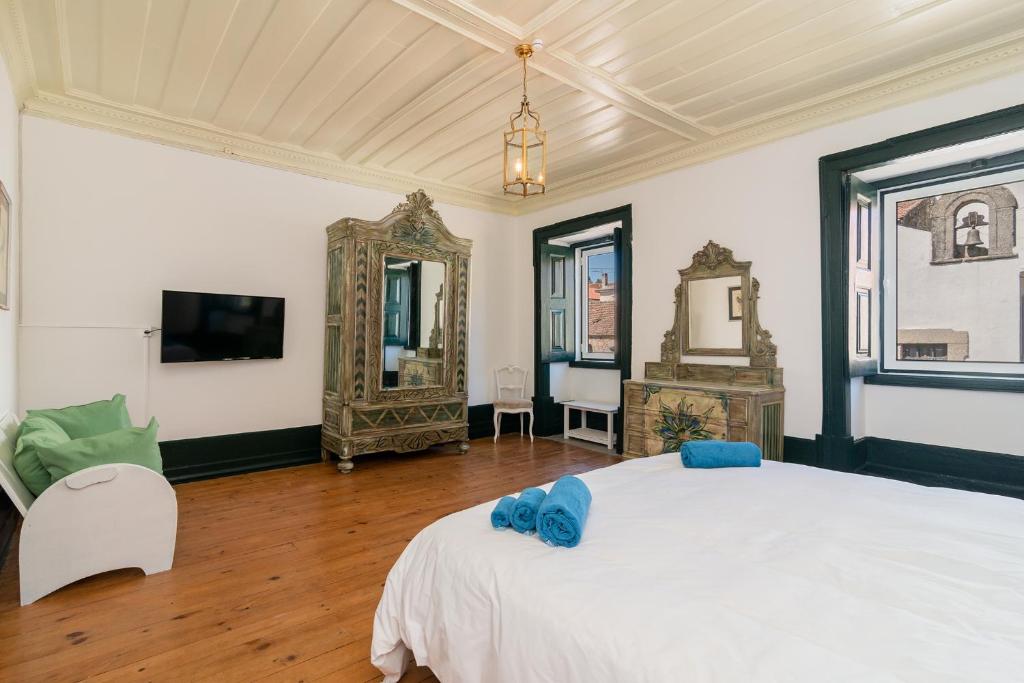 um quarto com uma cama branca e um espelho em Casa de Lagarinhos JACUZZI SPA JOGOS GYM - SERRA DA ESTRELA - SEIA - GOUVEIA em Gouveia