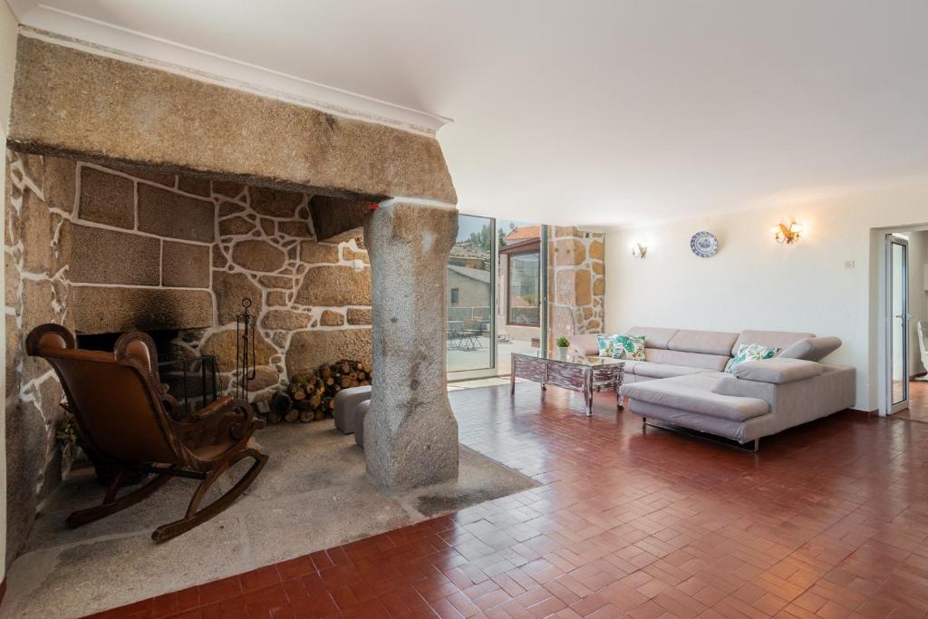 uma sala de estar com uma lareira de pedra e um sof em Casa de Lagarinhos JACUZZI SPA JOGOS GYM - SERRA DA ESTRELA - SEIA - GOUVEIA em Gouveia