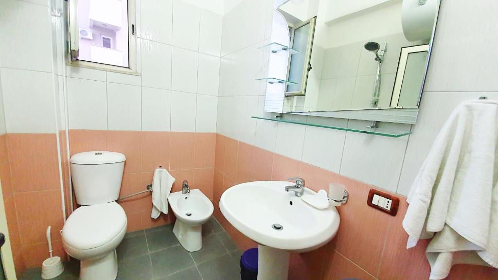 La salle de bains est pourvue de toilettes, d'un lavabo et d'un miroir. dans l'établissement Vila Vera, à Durrës