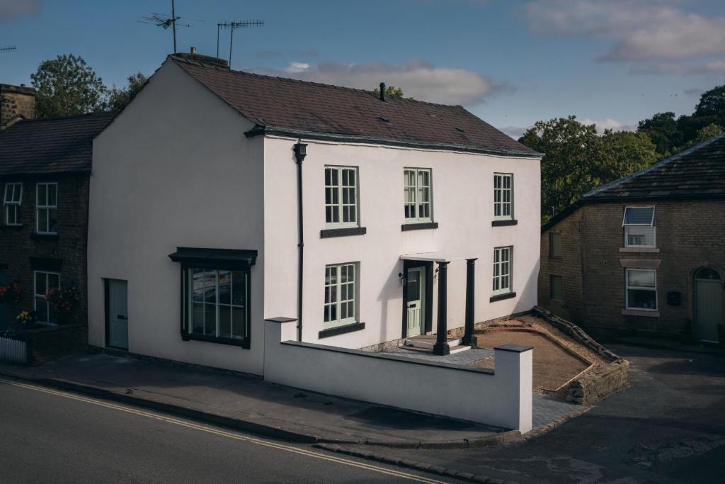 Basin House Peak District في Whaley Bridge: بيت ابيض جالس على جانب شارع