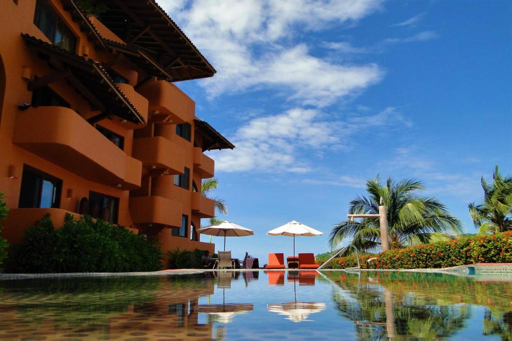 una piscina junto a un edificio con sombrillas en Hotel la Quinta de Don Andres en Zihuatanejo