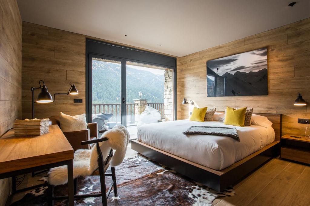 Luxury Ski Chalet Andorra في سولديو: غرفة نوم بسرير كبير ومكتب ونافذة