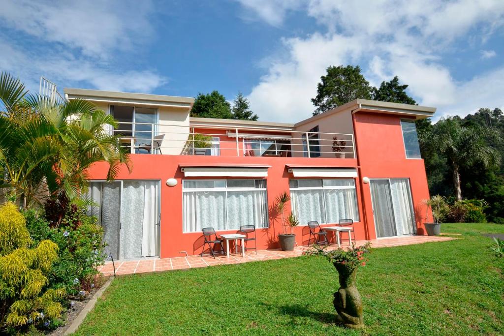 una casa roja con mesas y sillas en un patio en Supercostarica en Grecia