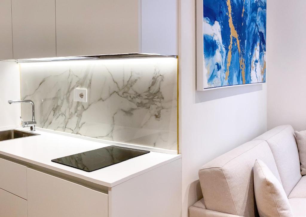 una cucina bianca con lavandino e divano di La Ripa Camere Vernazza - Stradivari Luxury Apartment a Vernazza