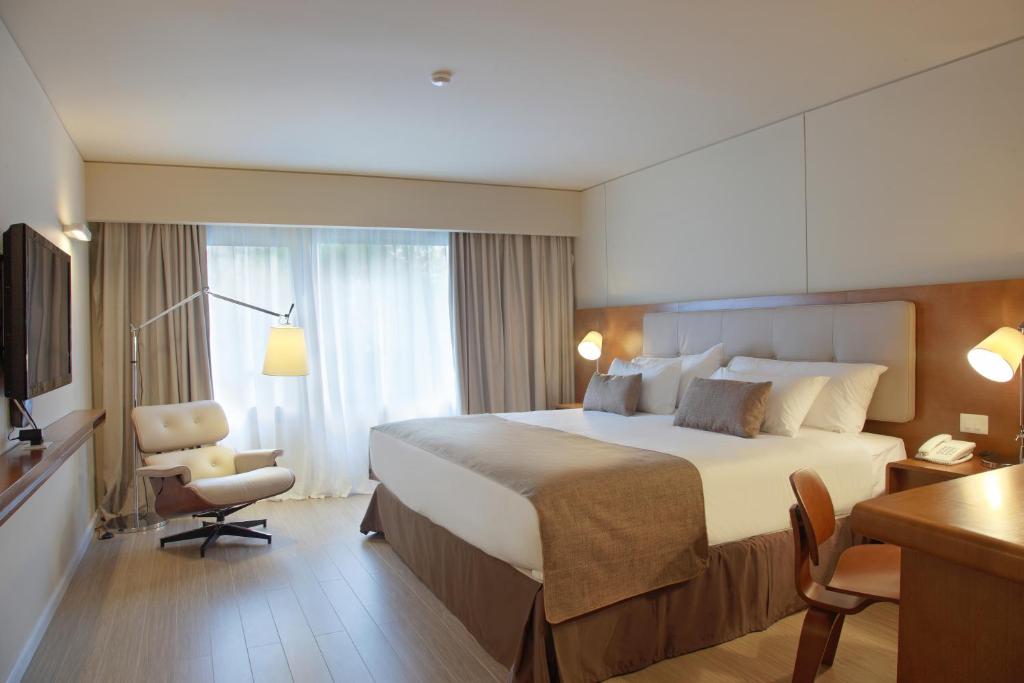 um quarto de hotel com uma cama grande e uma cadeira em Dazzler by Wyndham Montevideo em Montevidéu
