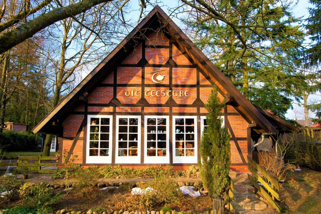 Una casa de madera con un cartel en el costado. en FeWo Katharina (Teestube Undeloh) Lüneburger Heide, en Undeloh