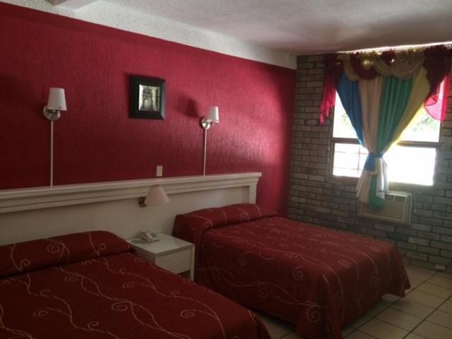 1 dormitorio con paredes rojas, 1 cama y ventana en Hotel Raldos Inn, en Salamanca