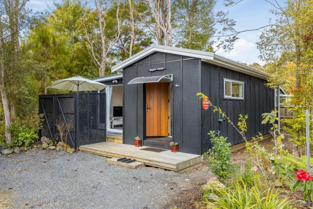 Ein schwarzes winziges Haus im Wald. in der Unterkunft Bellbird Cottage - Lake Taupo Bach in Waitahanui