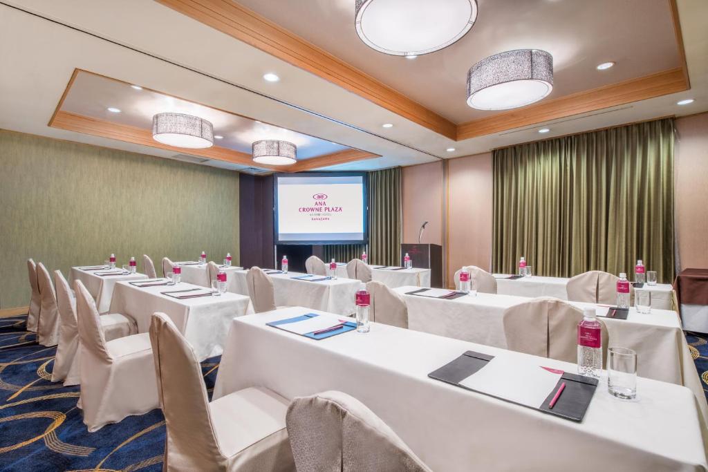 a conference room with white tables and chairs and a screen at ANA Crowne Plaza Kanazawa by IHG in Kanazawa
