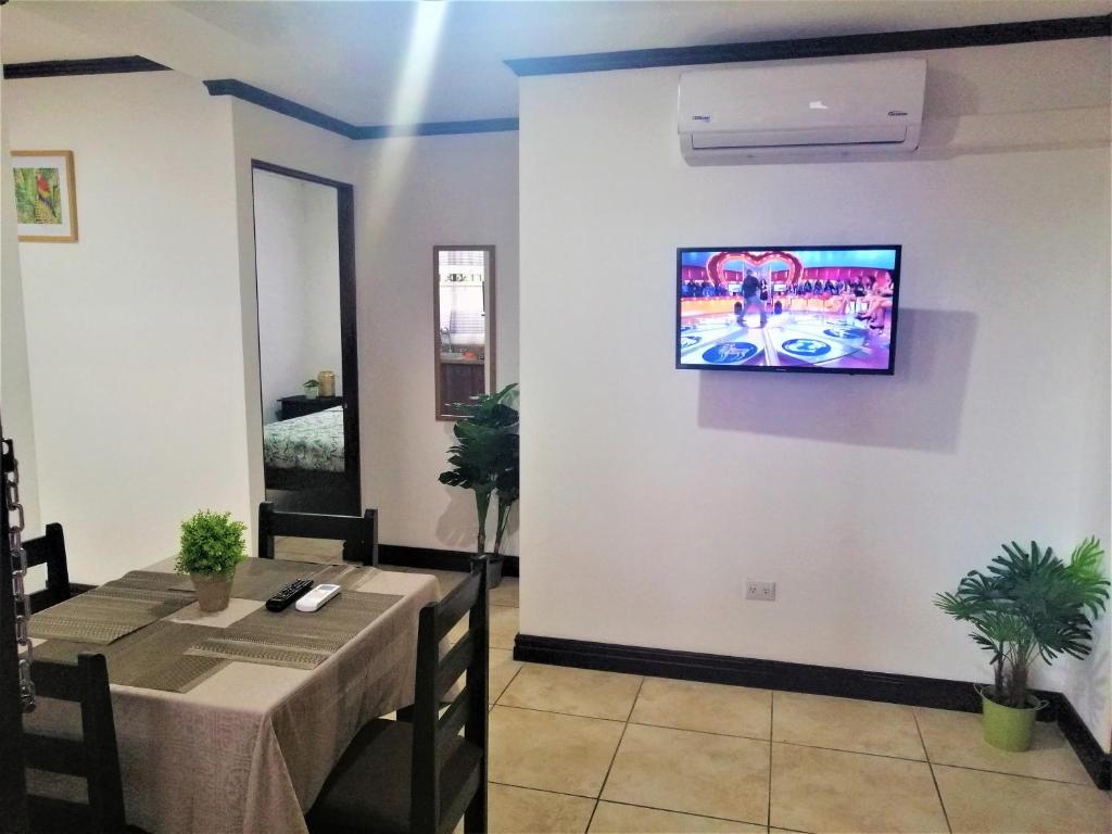 a dining room with a table and a tv on the wall at Kubo Apartment Private 2 Bedrooms 5 mins SJO Airport with AC in Alajuela City