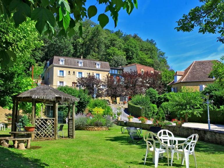 een tuin met stoelen en een prieel en een gebouw bij Hôtel Restaurant Plaisance-Piscine couverte et chauffée- Proche Sarlat- in Vitrac