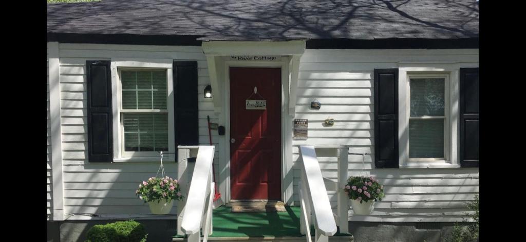 a white house with a red door and flowers at Rappahannock River Cottage Near I-95! in Fredericksburg