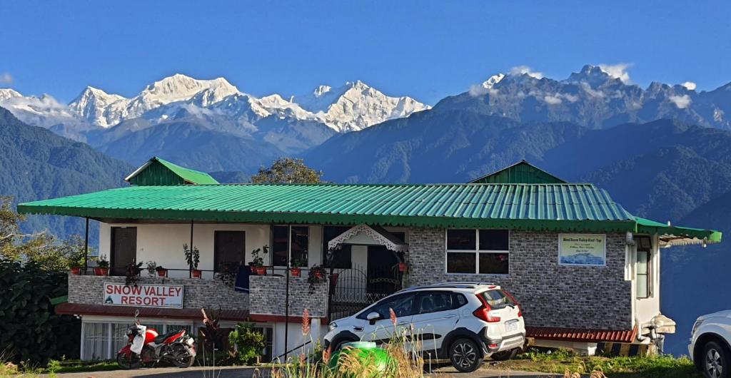 a house with a car parked in front of it with mountains at Hotel Snow Valley Rooftop in Pelling