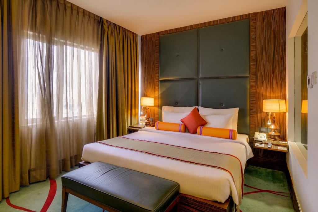 um quarto de hotel com uma cama grande e uma janela em Pride Hotel, Chennai em Chennai