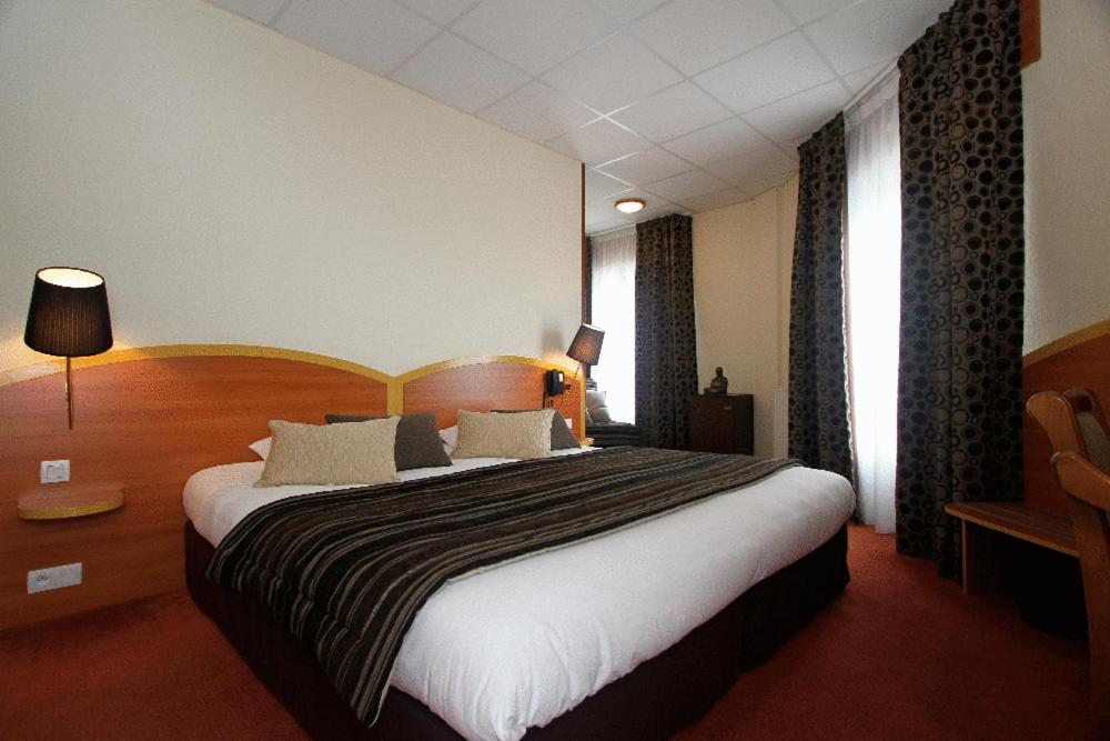 a hotel room with a bed and two nightstands at Kyriad Hotel Lamballe in Lamballe
