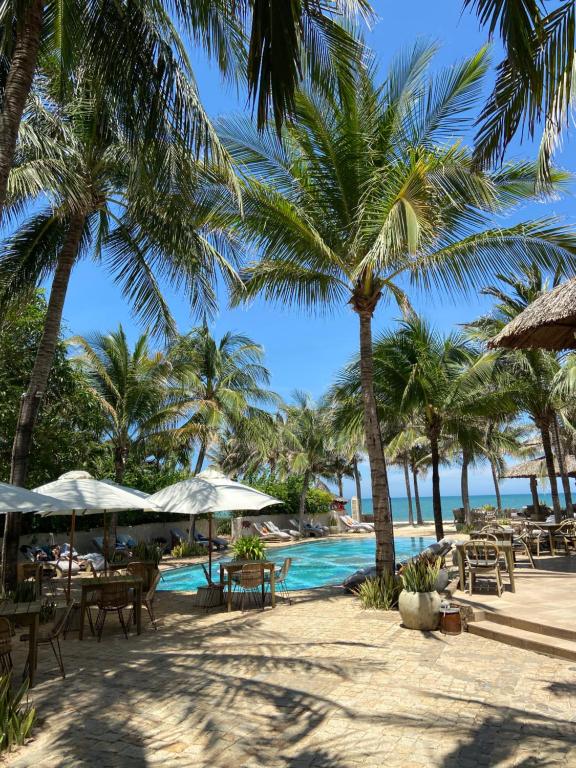 un complexe avec des palmiers et une piscine dans l'établissement Sailing Club Resort Mui Ne, à Mui Ne