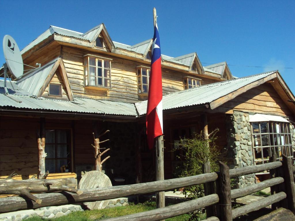 una cabaña de madera con una bandera delante de ella en Hosteria Rayen, en La Junta