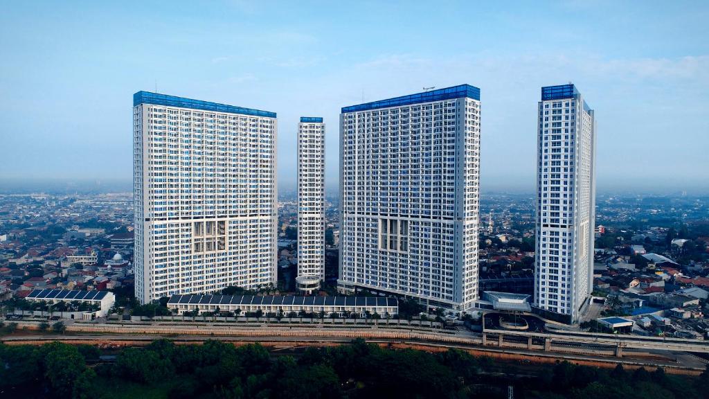 três arranha-céus altos numa cidade com em Harris Suites Puri Mansion em Jakarta