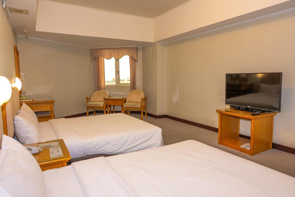 a hotel room with two beds and a flat screen tv at Kenting City Gate Hotel in Hengchun South Gate