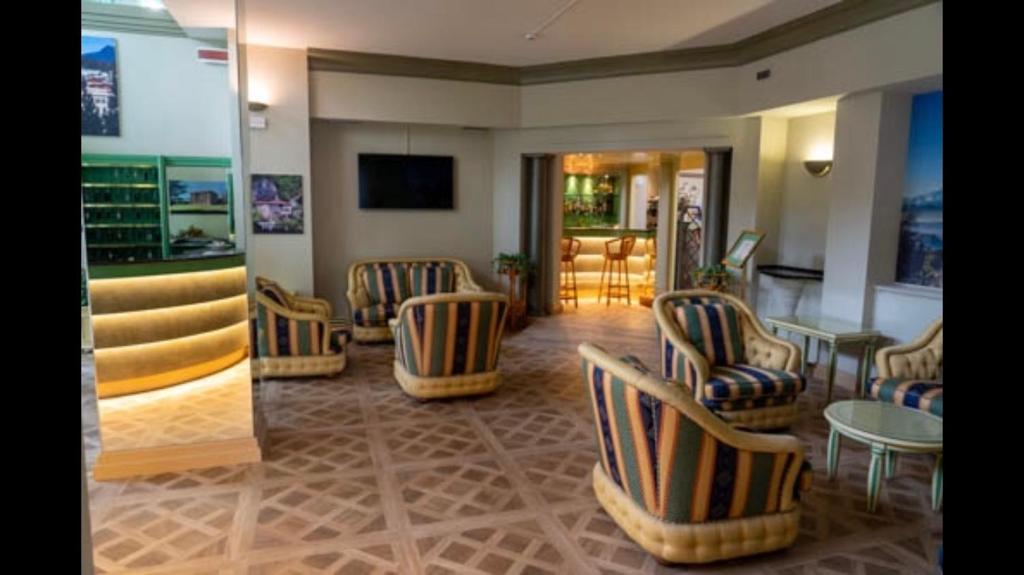 a waiting room with chairs and tables and a television at Crystal Hotel Varese in Varese