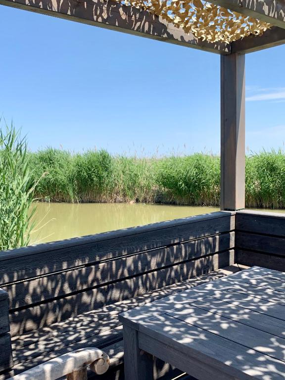 a deck with a table and a view of a river at Seehütte Neusiedlersee inklusive Boot in Rust