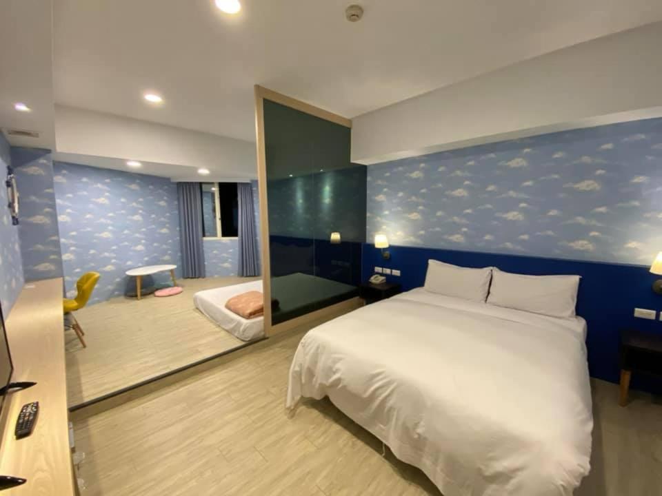 a bedroom with a white bed and a blue wall at Kenting City Gate Hotel in Hengchun South Gate