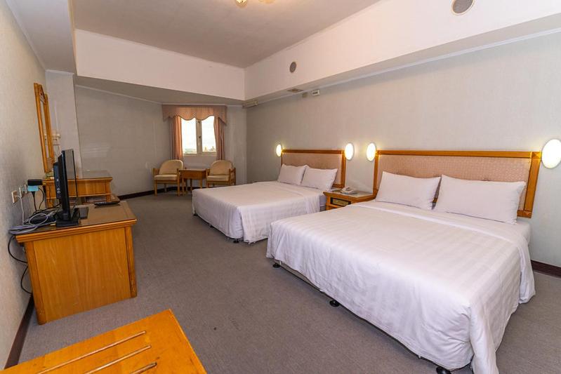 a hotel room with two beds and a flat screen tv at Kenting City Gate Hotel in Hengchun South Gate