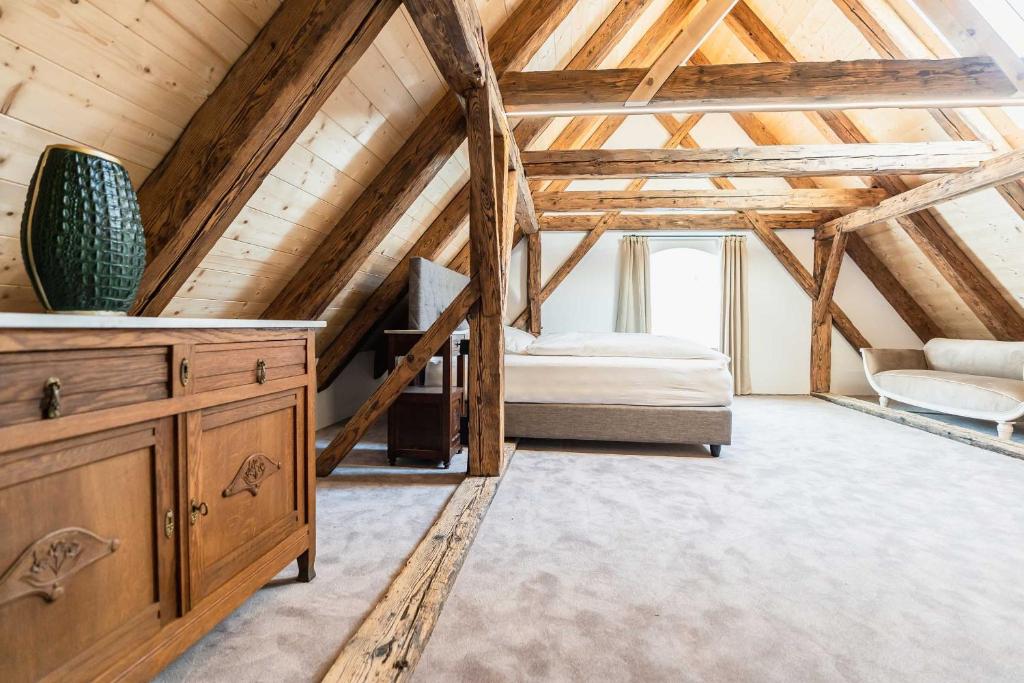 a large attic room with a bed and a staircase at Altstadthotel Bachbräu in Weilheim in Oberbayern