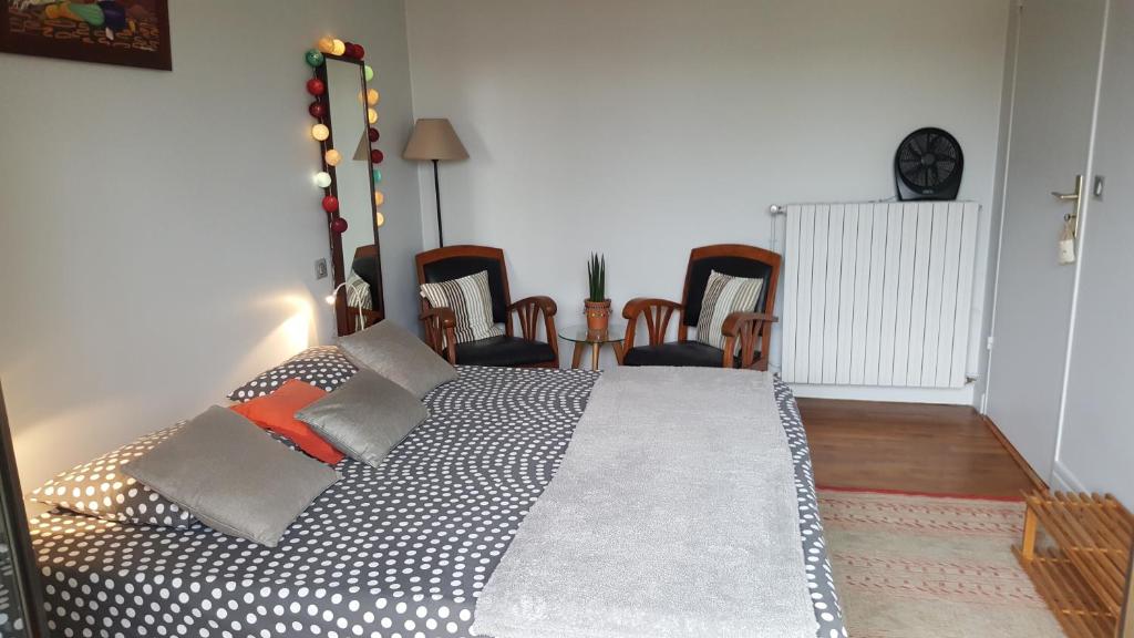 a bedroom with a large bed in a room with chairs at Margouillat chambre d'hôte in Figeac