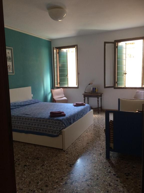 a bedroom with a bed and two windows at Cà Greta in Venice