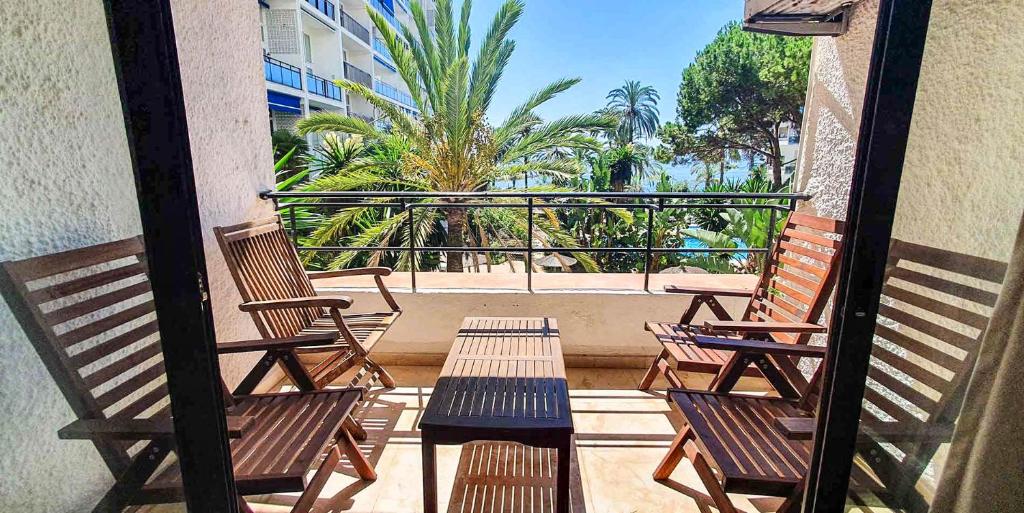 3 sillas y mesas en un balcón con palmeras en SKOL 233. Wonderful Two Bedroom Apartment in Marbella Center., en Marbella