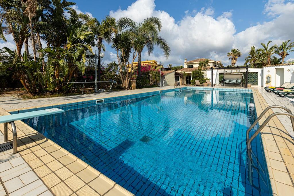 uma grande piscina com água azul em Solemar Sicilia - Villa Anastasia em Ficarazzi