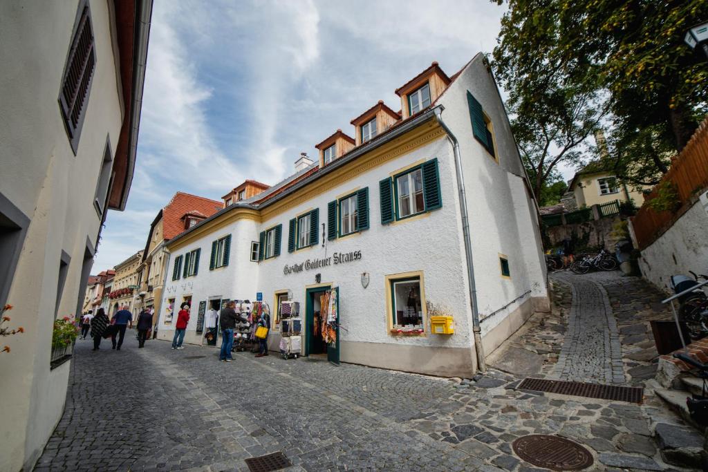 a group of people walking down a street next to a building at Smile Apartments zum Goldenen Strauß in Dürnstein