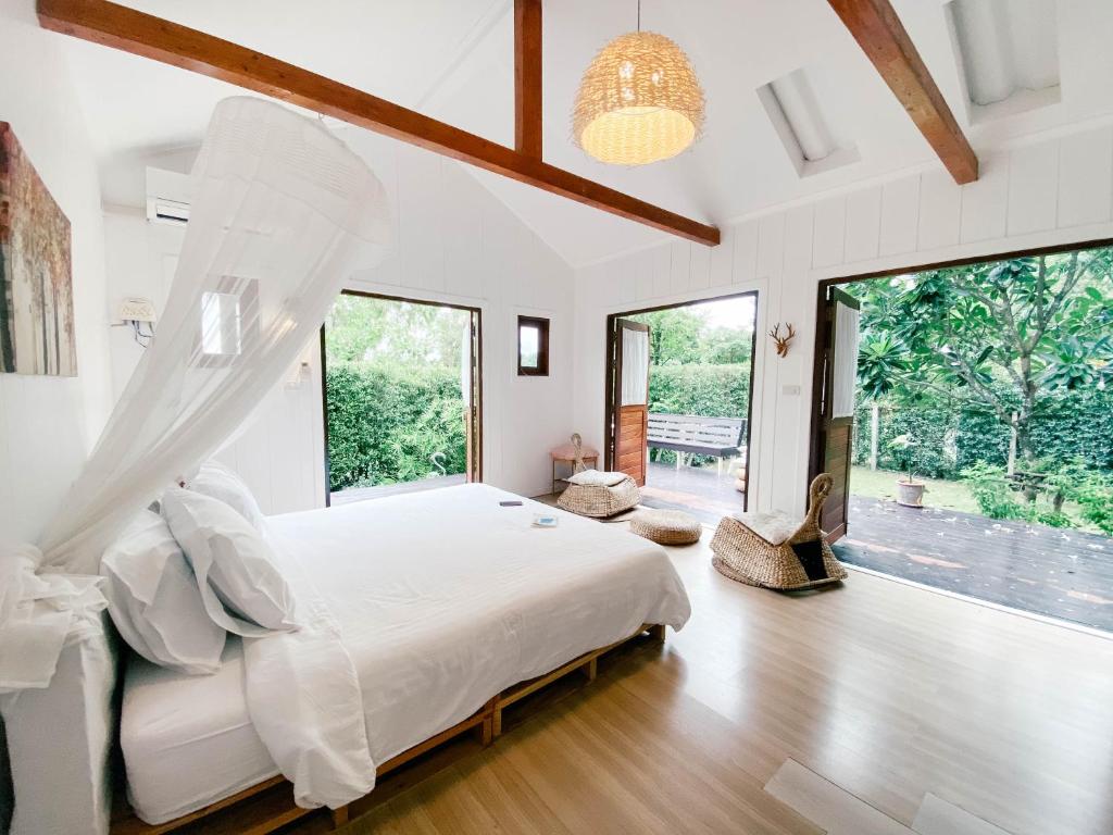 - une chambre avec un grand lit et de grandes fenêtres dans l'établissement Terrua Main Ten Villa Garden, à Suan Phueng