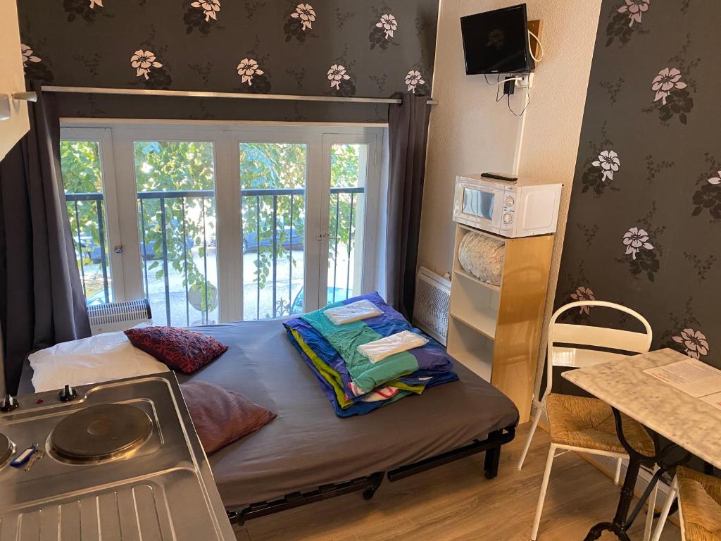 - une petite chambre avec un lit et une fenêtre dans l'établissement Les studios meublés de l'avenue Bouloumié Vittel, à Vittel