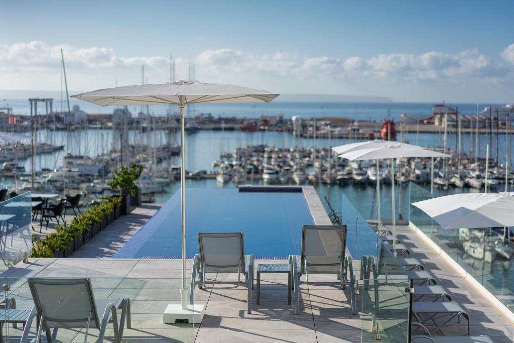 einen Pool mit Stühlen und Sonnenschirmen neben einem Yachthafen in der Unterkunft Hotel Mirador in Palma de Mallorca