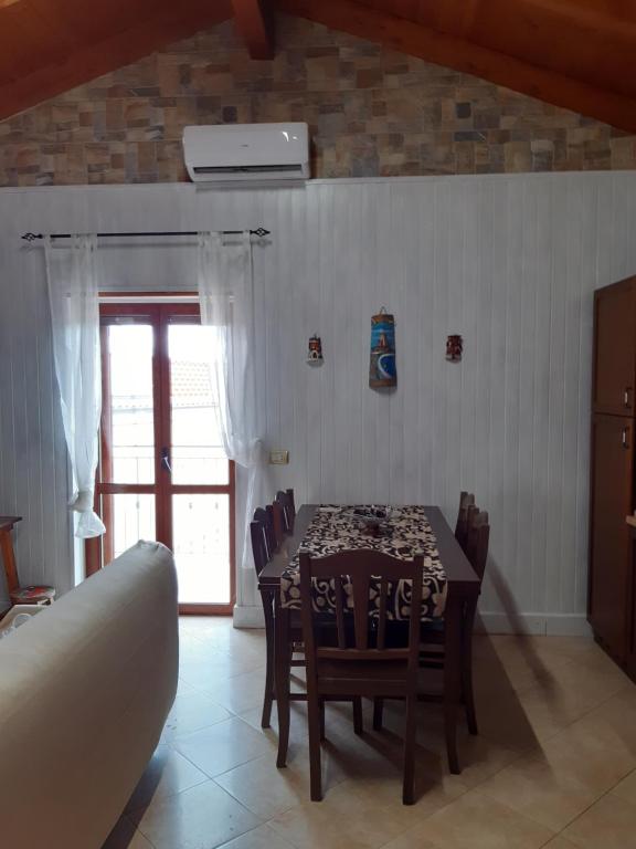 ein Esszimmer mit einem Tisch, Stühlen und einem Fenster in der Unterkunft Il Murales Montegiordano in Montegiordano