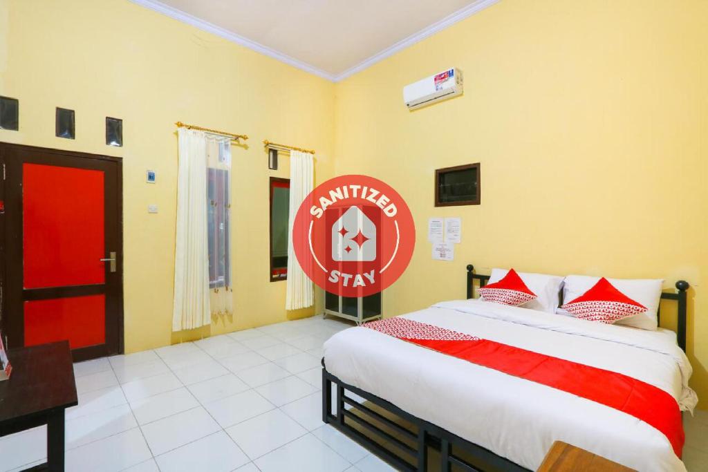 a bedroom with a bed with a red sign on the wall at OYO 3100 El Shaday Family Residence in Banyuwangi