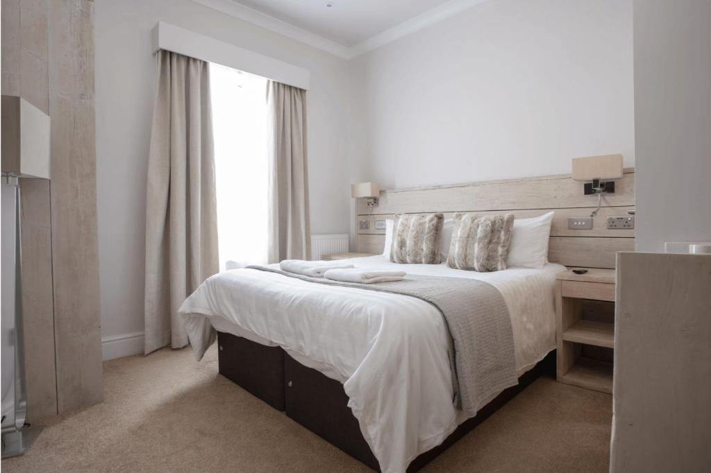 a white bedroom with a large bed and a window at The Vanguard York - Private Residence in York