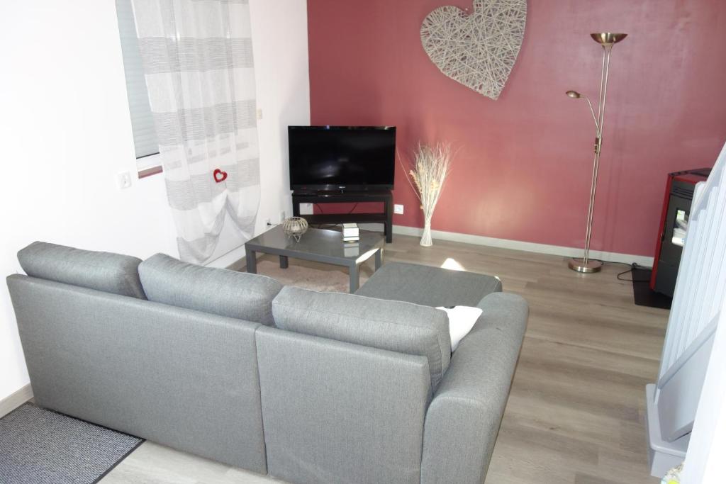uma sala de estar com um sofá e uma televisão em Home Bigarreaux em Le Mans