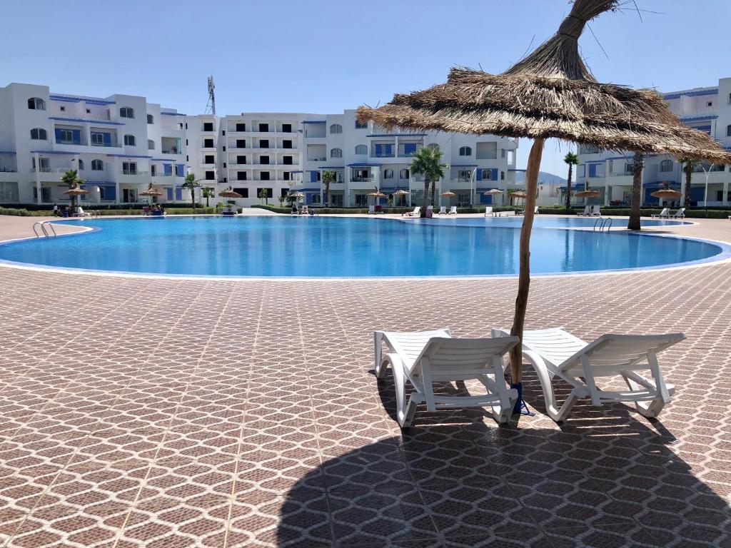 two chairs and an umbrella next to a swimming pool at Brand new Beautiful Vacation house - Family Only in Cabo Negro