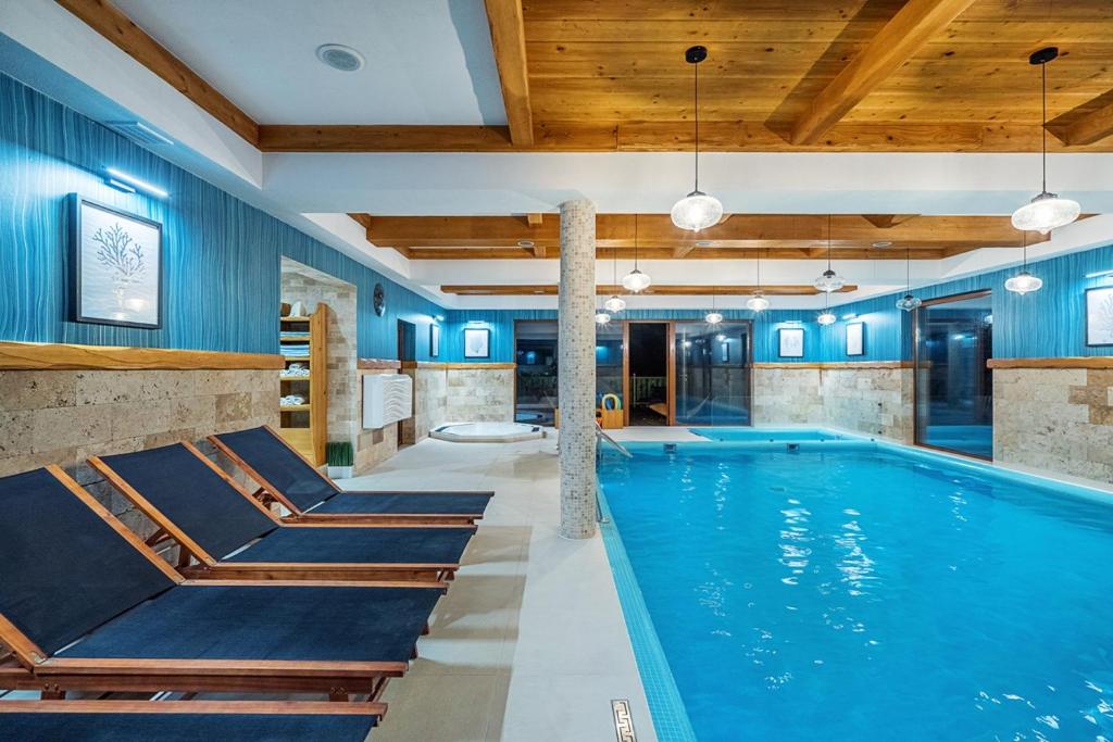 a swimming pool with blue walls and wooden ceilings at Villa Źródło & Spa in Krynica Zdrój