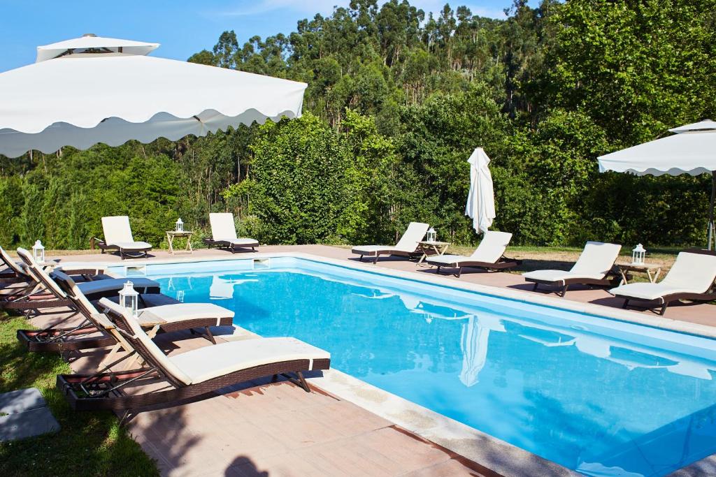 a swimming pool with lounge chairs and an umbrella at Quinta do Lordelo Turismo Rural in Penafiel
