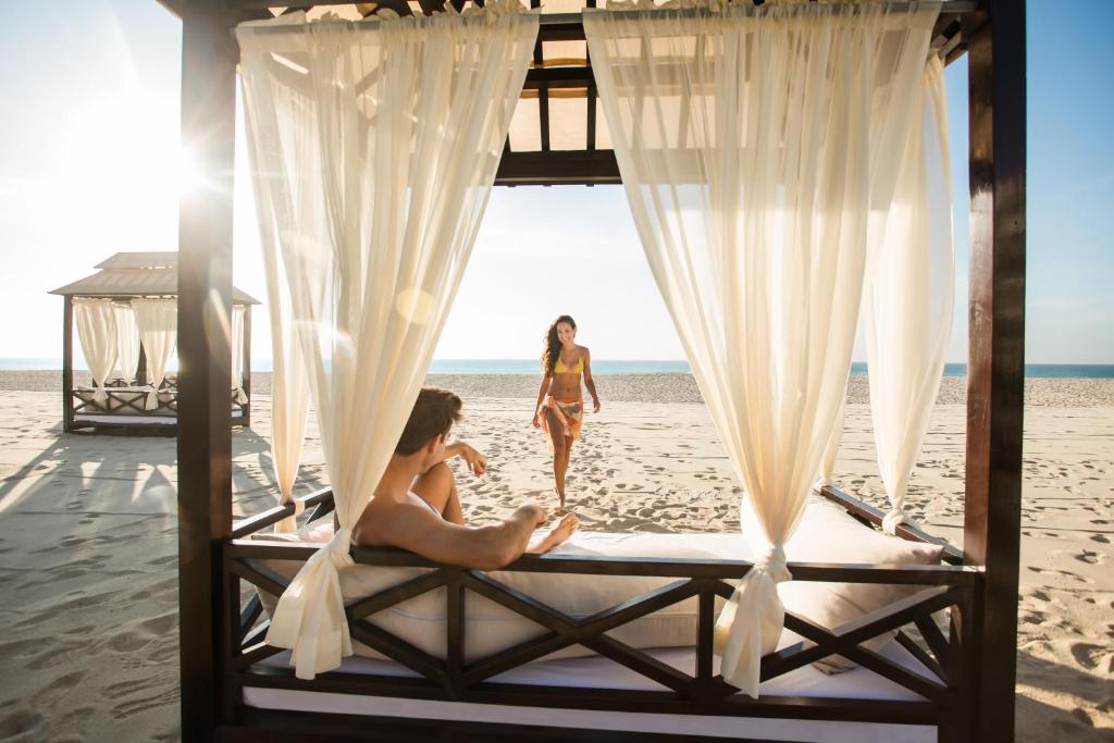 two women walking on the beach with a bed on the beach at Hyatt Ziva Los Cabos - All Inclusive in San José del Cabo